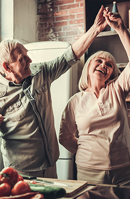 Older man and women smiling and dancing in kitchen