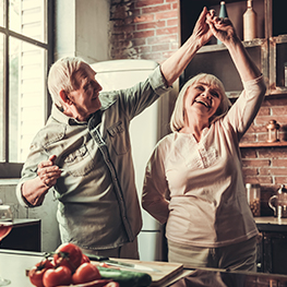 Older man and women smiling and dancing in kitchen