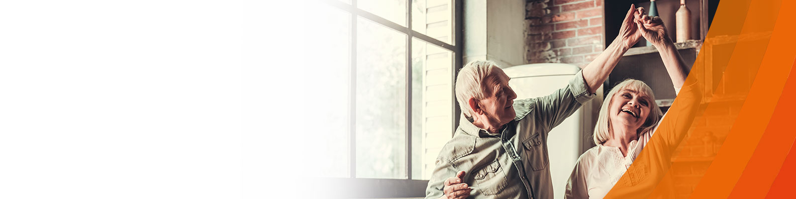 Older man and women smiling and dancing in kitchen with orange voltaren colours