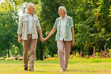 Older couple walking through a park holding hands