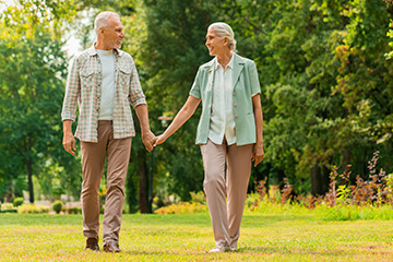 Taking a walk Older couple walking through a park holding hands
