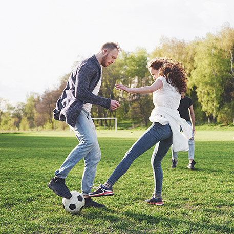 Friends playing football on open field on a sunny day