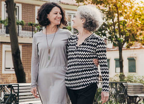 Younger woman and older woman walking together down a street