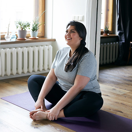 Woman sitting on yoga mat and stretching her legs