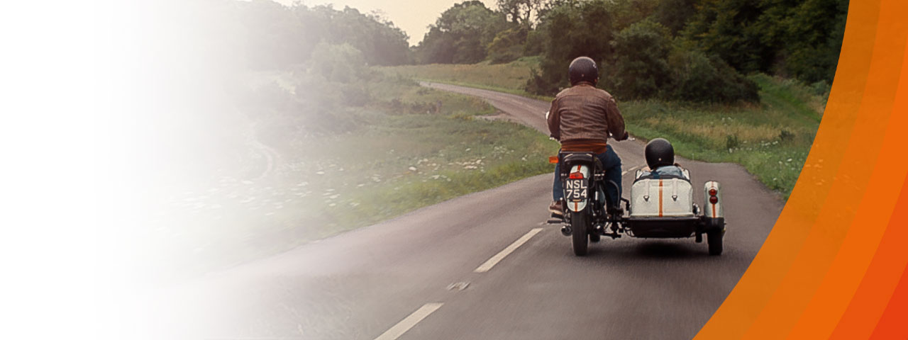 Man on motercycle with child in sidecar