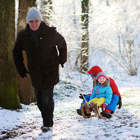 A man pulling his son on a sledge in the snow without back pain