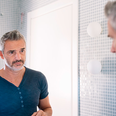 Man looks in bathroom mirror 