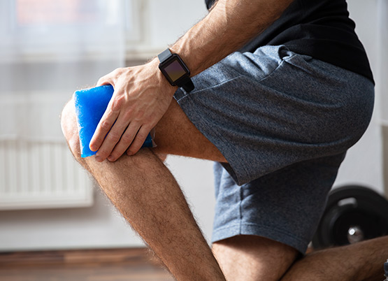 Man uses ice pack on knee pain as part of RICE method 