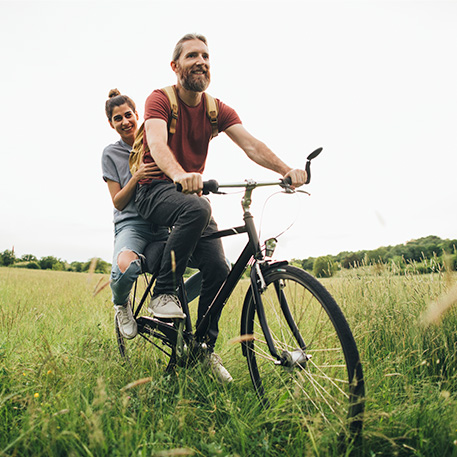 man and woman riding a bike pain free in a field 